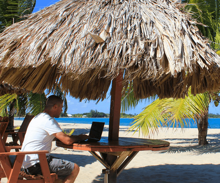 Guy working on beach laptop